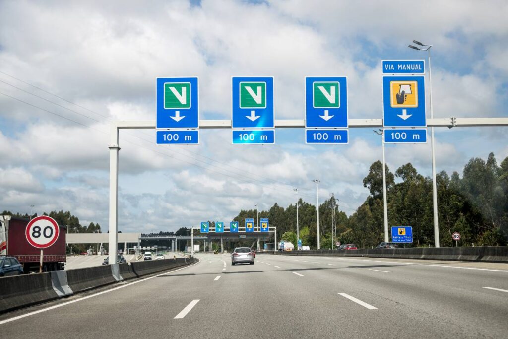 Imagem de uma seção da autoestrada A3 em Portugal, com sinalização de portagens e limite de velocidade, ilustrando as regras de trânsito para circulação segura.