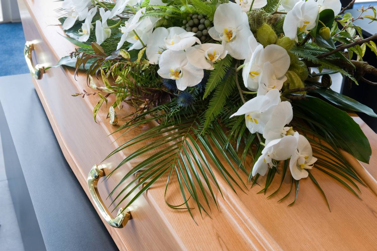 Imagem de um caixão com flores, simbolizando o luto e a importância do subsídio por morte, um apoio financeiro destinado aos familiares do falecido para ajudar com as despesas após o falecimento.