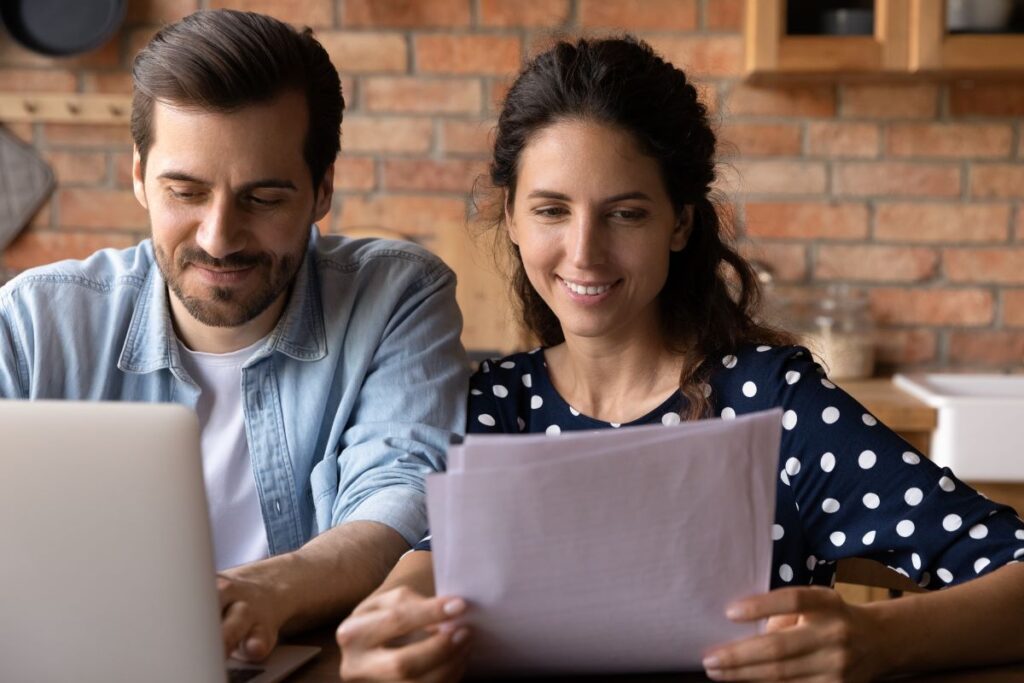 Casal a analisar documentos, representando os benefícios do Programa de Arrendamento Acessível (PAA).