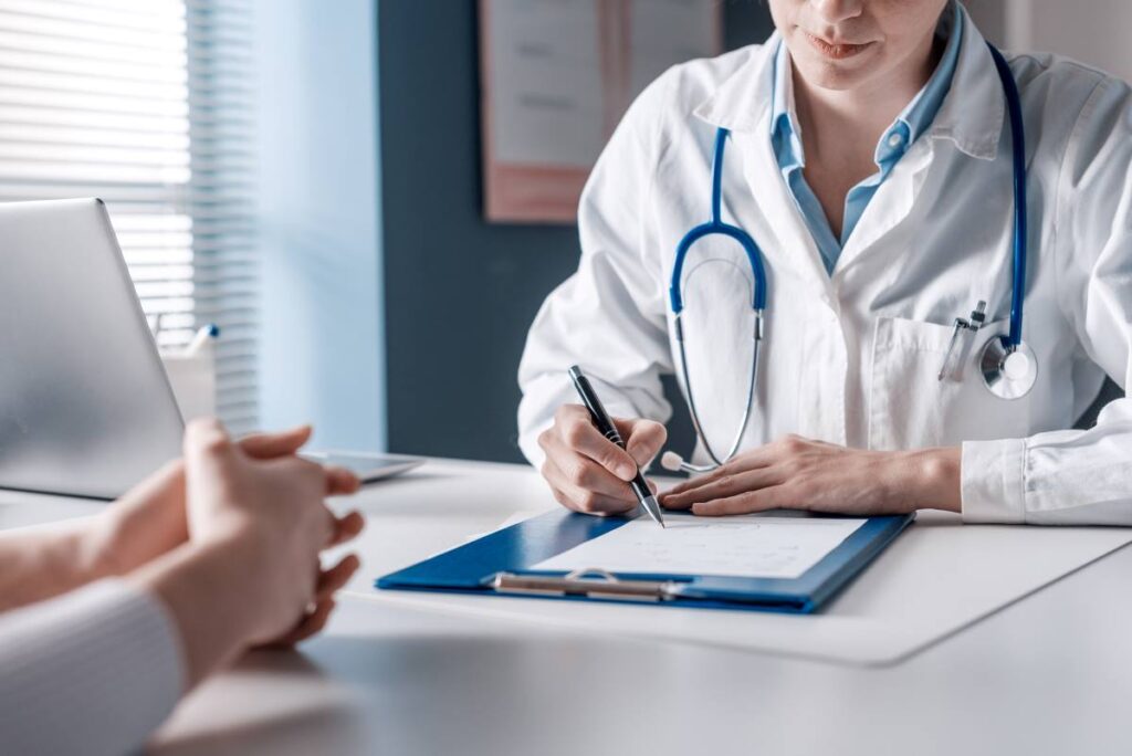 Médico sentado à secretária a preencher um formulário, com um estetoscópio ao redor do pescoço, simbolizando a importância do processo de obtenção do Número de Utente Provisório no sistema de saúde.