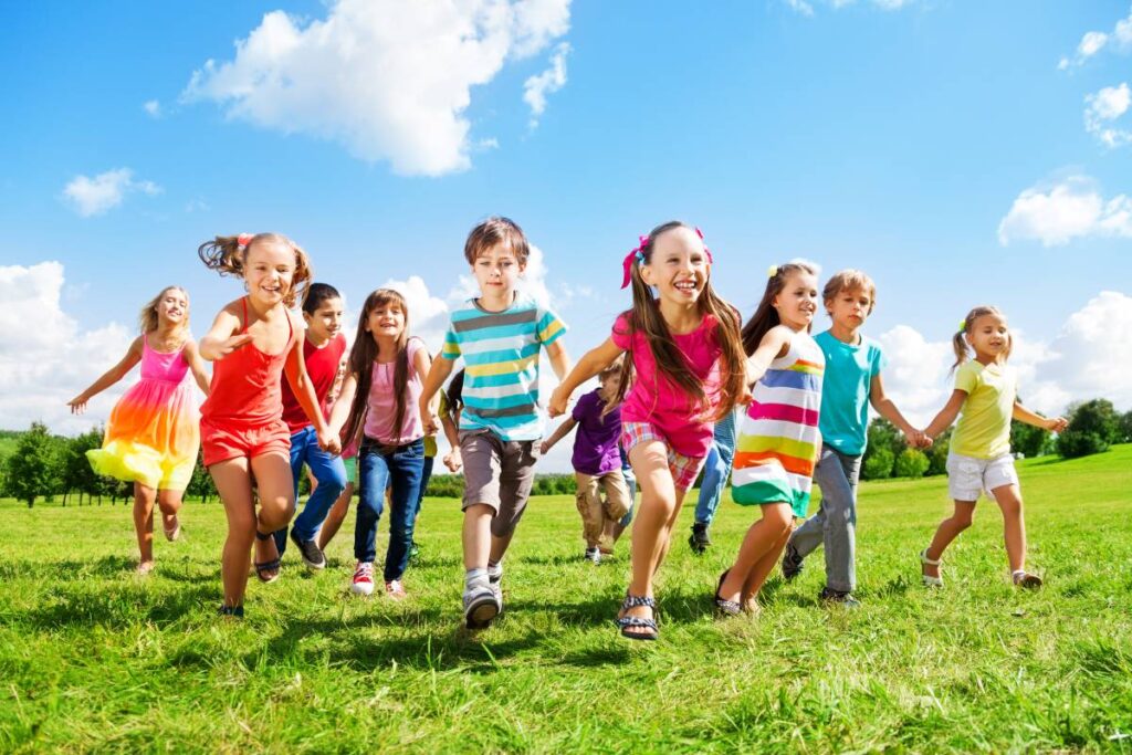 Imagem de crianças correndo ao ar livre, simbolizando a diversão e as atividades durante as férias escolares 2025-2026, um período esperado de descanso e lazer para os estudantes.