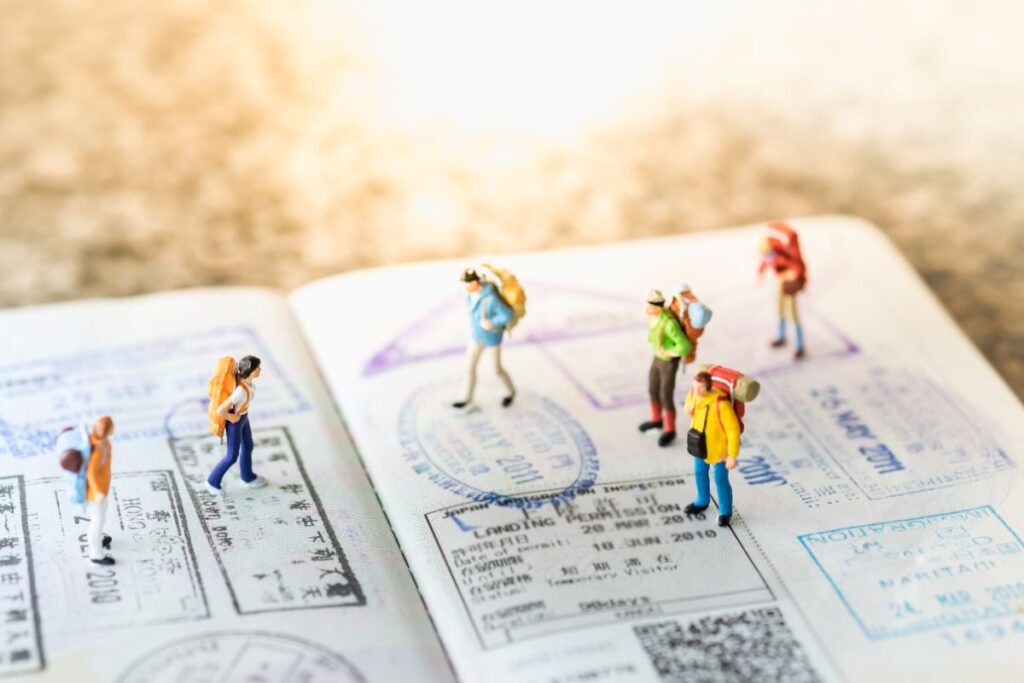 A imagem ilustra um passaporte com pessoas e ilustra as férias pelo mundo. Evite as férias não gozadas.