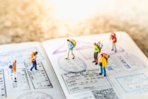 A imagem ilustra um passaporte com pessoas e ilustra as férias pelo mundo. Evite as férias não gozadas.