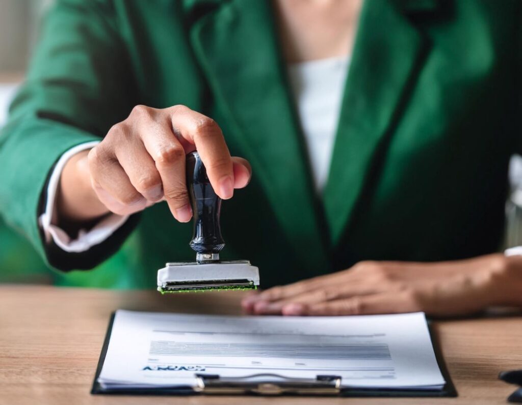 Pessoa a aplicar um carimbo em um documento, simbolizando o processo de regularização de imigrantes em Portugal.