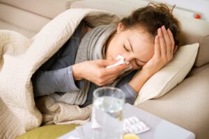 Trabalhadora doente em casa com sintomas de gripe, a repousar no sofá, exemplo de situação em que pode pedir baixa médica de 3 dias online no SNS 24.